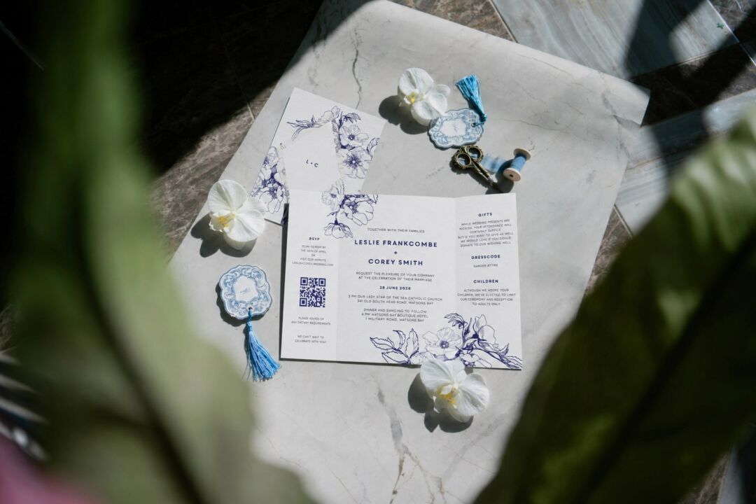 A Paperlust wedding invitation suite laid out on marble in hard afternoon light.