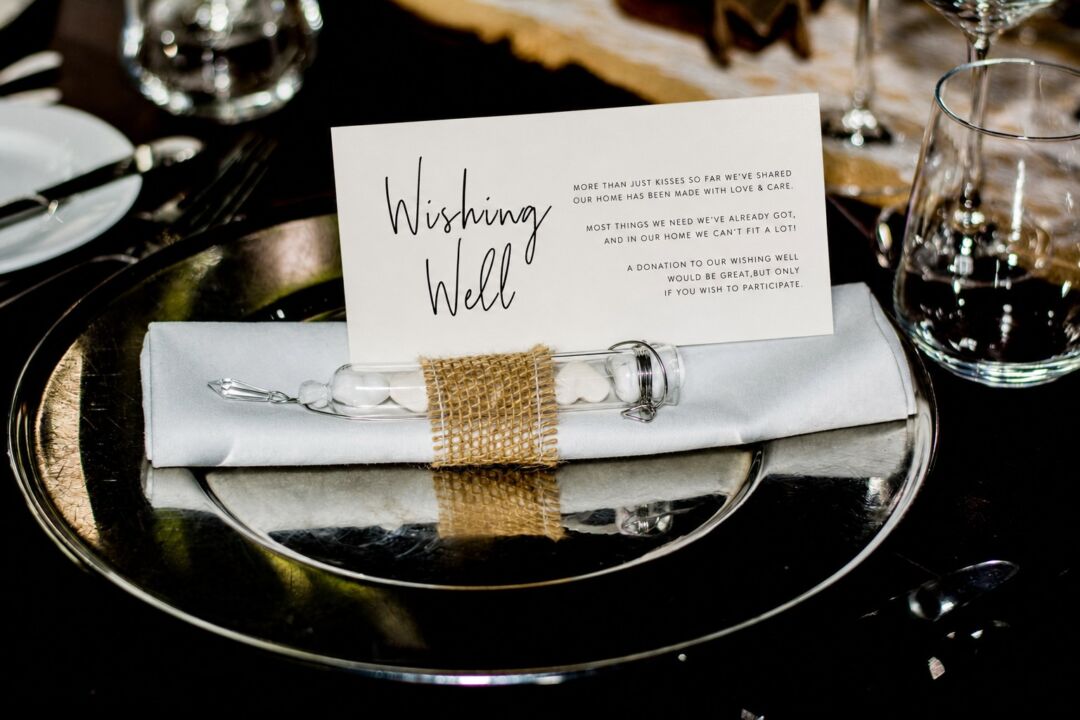 An elegant place setting features a white napkin tied with burlap ribbon holding a small glass bottle.