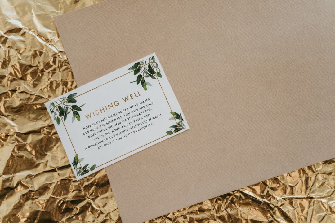 A 'Wishing Well' card with green leaf borders sits on crumpled gold tissue paper against a beige background.