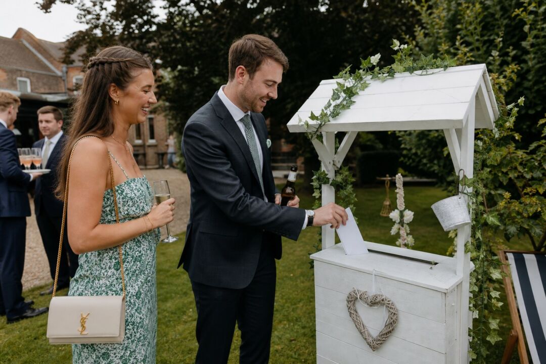 Two smartly dressed wedding guests at an outdoor garden reception.