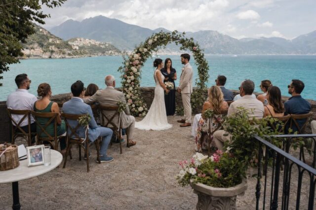 A small destination wedding ceremony on a stone terrace overlooking turquoise ocean water.