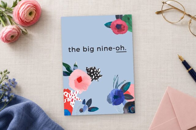 Paperlust Abstract Floral invitation in periwinkle blue with painted pink and red flowers reads the big nine oh on linen.