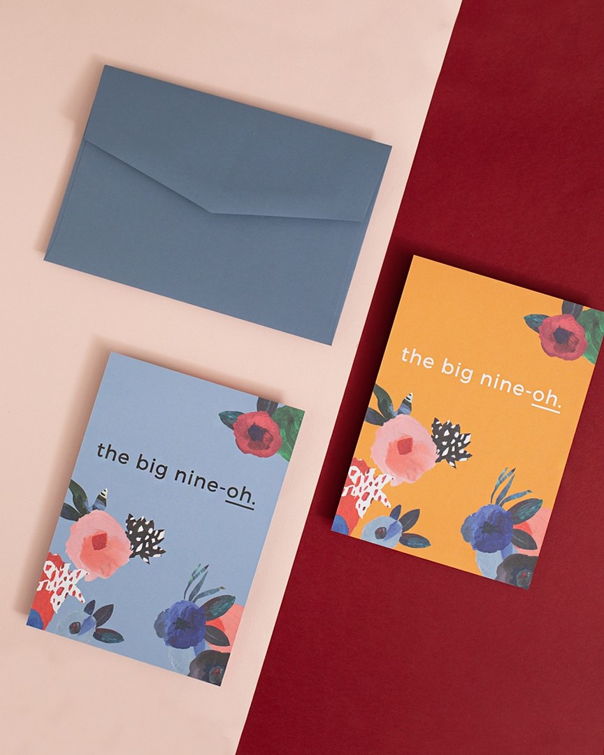 Paperlust Abstract Floral two birthday cards in pale blue and orange with painted flowers lie on split pink and red paper.