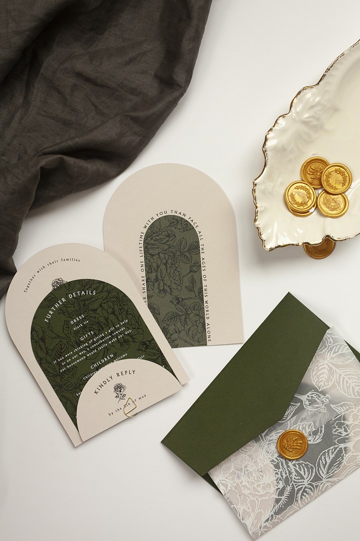 Paperlust Array cream arch stationery set on a white surface has a dark green rose arch panel and gold wax seal on vellum.