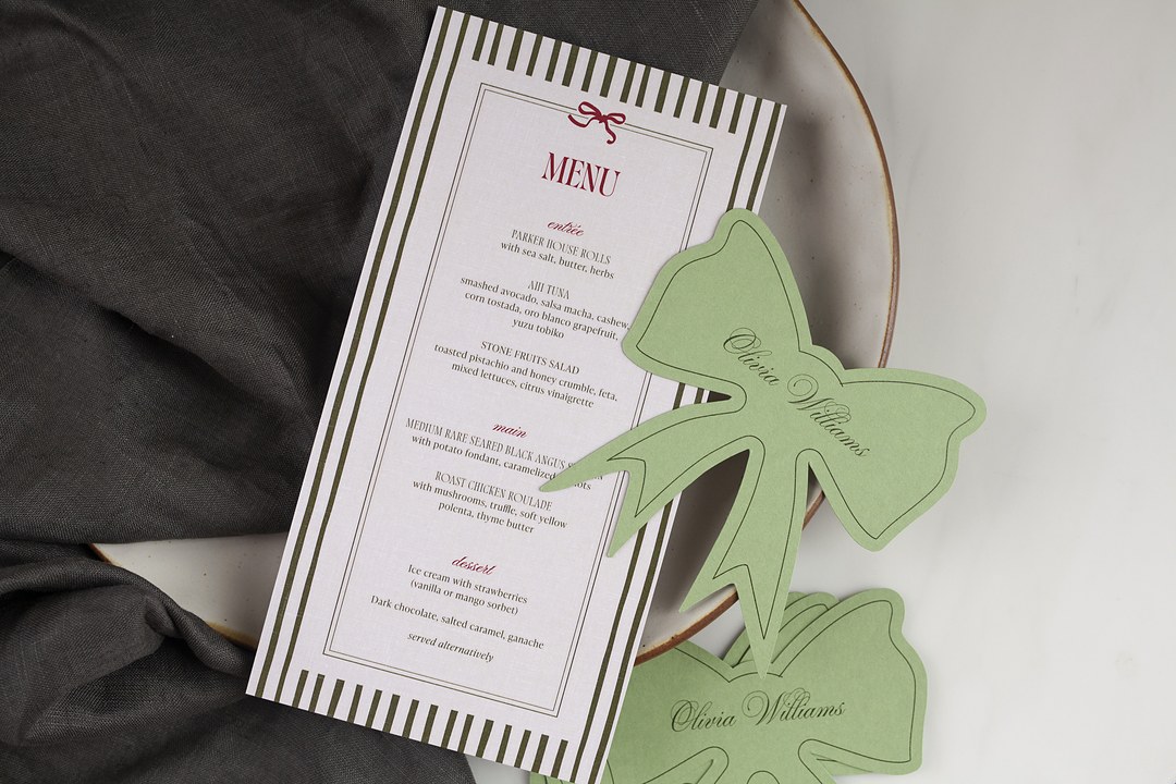 Paperlust Bow Stripes is a tall wedding menu card with olive green stripes and a red bow on a cream stoneware plate.