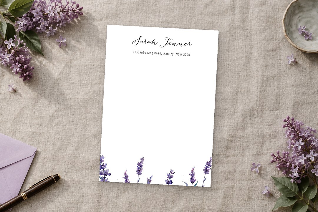 Paperlust Lavendula notecard lies on oatmeal linen with watercolor lavender stems, a pale lilac envelope, and a wooden pen.