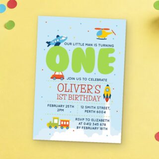 Paperlust Planes Trains Cars Birthday Invitation rests on a yellow surface beside wooden stacking rings and round confetti.