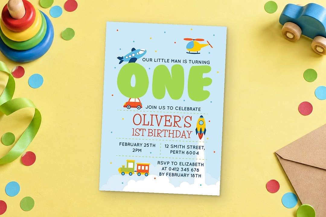 Paperlust Planes Trains Cars Birthday Invitation rests on a yellow surface beside wooden stacking rings and round confetti.