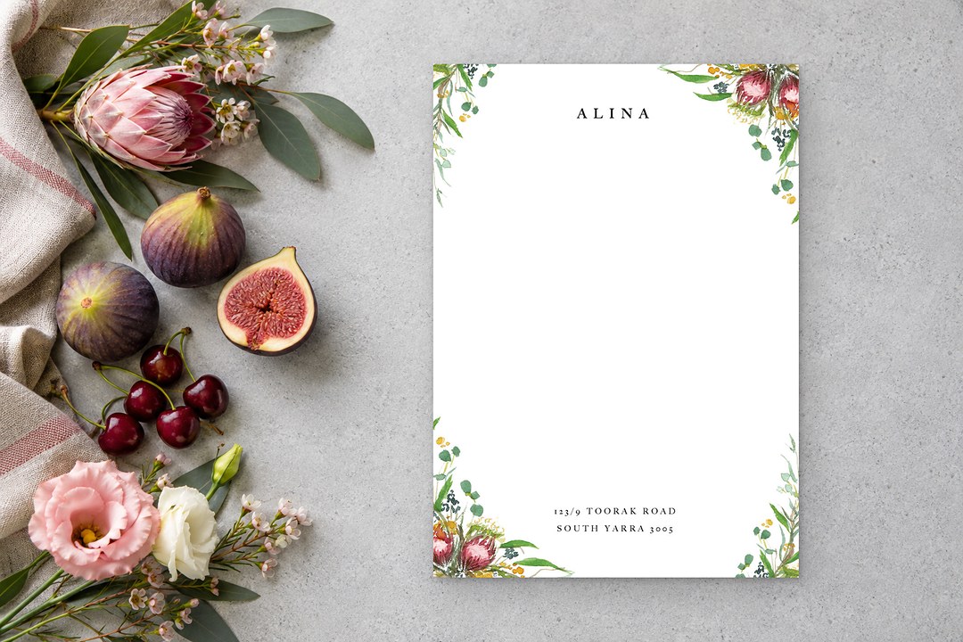 Paperlust Sarulean notecard printed with ALINA and an address shows pink proteas, eucalyptus and yellow blossoms on gray concrete.