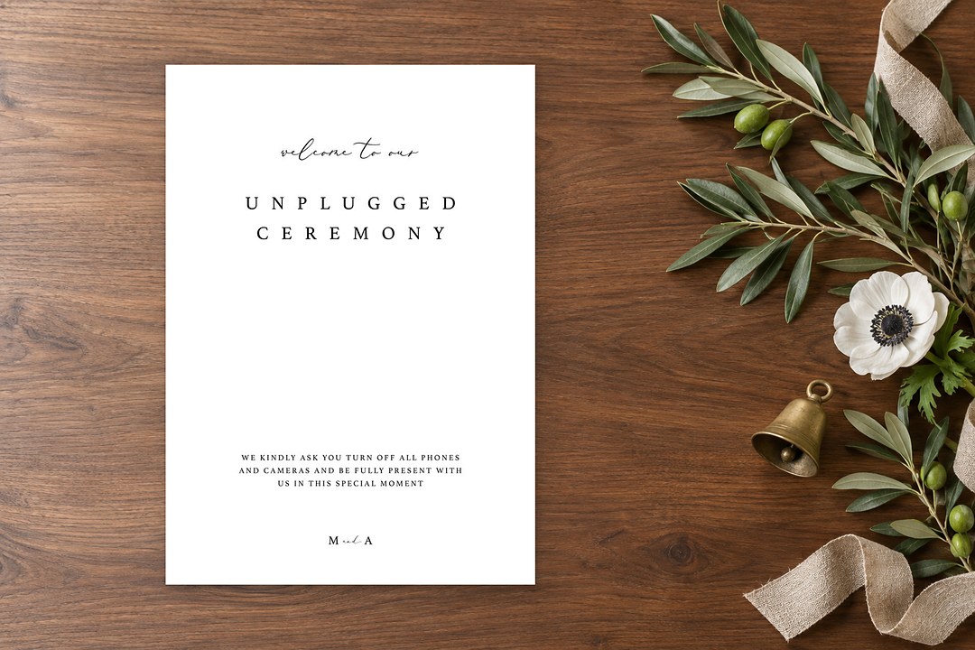 Paperlust Together sign on walnut wood with olive branches and a white anemone shows unplugged ceremony wording with an M and A monogram.